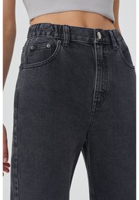 Jeans en denim noir taille haute avec un tissu texturé, dotés d'une fermeture à bouton, de passants de ceinture et de poches avant.