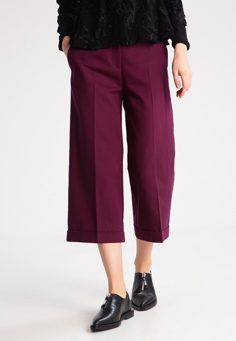 Bordeaux cropped trousers met een wijd been, met een gladde textuur en persplooien. Gecombineerd met zwarte oxford schoenen.