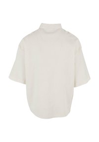 Camicia beige in lino a maniche corte con una vestibilità comoda. Presenta un colletto e un orlo arrotondato, con tessuto di peso medio e trama minima.