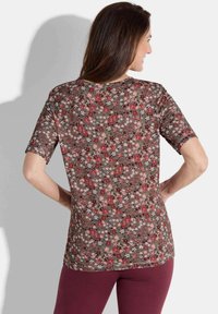 T-shirt à manches courtes avec un motif floral brun comportant des fleurs rouges, blanches et roses. Tissu doux avec un col rond et une coupe décontractée.