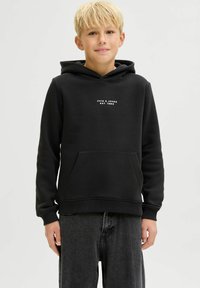 Sudadera negra con bolsillo frontal, que presenta un pequeño logotipo blanco. Material suave y puños acanalados, combinada con pantalones grises de corte relajado.