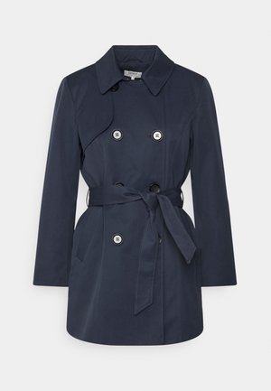 Trench-coat bleu marine à double boutonnage avec large col, détails boutonnés, poches latérales et ceinture nouée à la taille.