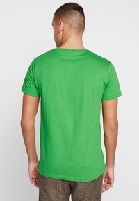 Grøn kortærmet t-shirt med rund halsudskæring. Fremstillet af glat stof, den har en regular fit og vises fra bagsiden.