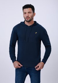 Marljivo plava dukserica s kapuljačom, s prednjim kengur džepom, teksturiranim panelima i malim zlatnim logotipom na prsima. Napravljena od mekane tkanine.
