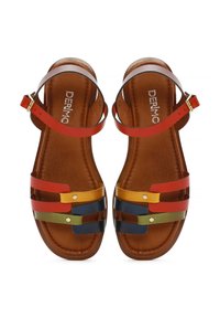 Sandalias planas multi-color con correas rojas, amarillas, verdes y azul marino sobre una plantilla de cuero marrón. Presentan una hebilla dorada y una textura suave.