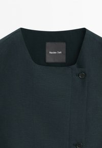 Dark gray garment with a square neckline, two black buttons on the right side, and a black label reading Massimo Dutti inside the collar.