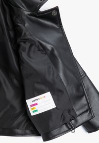 Zwarte neplederen jas met een interieur dat beschikt over een gladde, glanzende voering en een gelabeld label met kleurrijke iconen en verzorgingsinstructies.