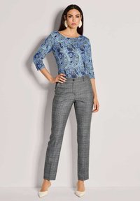 Blaues Top mit Paisley-Muster und Dreiviertelärmeln, kombiniert mit grauen karierten Slim-Fit-Hosen und beigen Absätzen. Glatte Stoffoberfläche.