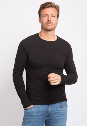 Zwart langemouw t-shirt met een ronde hals, gemaakt van een gladde stof, fitted ontwerp, gedragen met blauwe jeans. Eenvoudig en veelzijdig.
