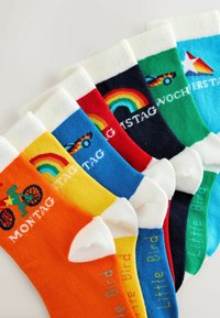 Calzini colorati con vari motivi: arancioni con una bicicletta, gialli con un arcobaleno, blu scuro con un arcobaleno e verdi con forme geometriche.