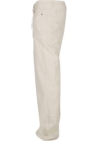 Beige cargo bukser med lige ben-design, der har flere lommer, slidte detaljer og snorelukning i taljen.