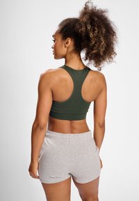 Ciemnozielony stanik sportowy z plecami w stylu racerback; w zestawie z jasnoszarymi szortami z miękkiego materiału; gładka tekstura, dopasowany krój.