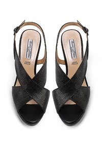 Scarpe slingback in pelle nera con texture stampata, punta chiusa e design incrociato sulla parte superiore. Inclusa una cinghia regolabile alla caviglia.
