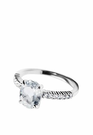 Anillo de plata con una gran piedra preciosa redonda y transparente en el centro y piedras pequeñas transparentes incrustadas a lo largo de la banda sobre un fondo blanco.