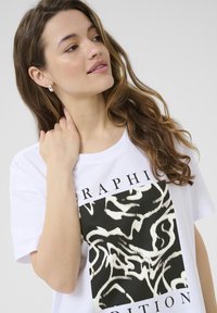 White graphic t-shirt featuring a black and white abstract design with bold lines. Soft cotton material with a relaxed fit.