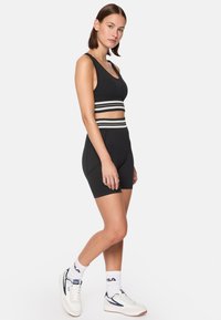 Svart träningsset som består av en kort topp med rundad halsringning och randig band, tillsammans med högmidjade shorts med en strukturerad yta.