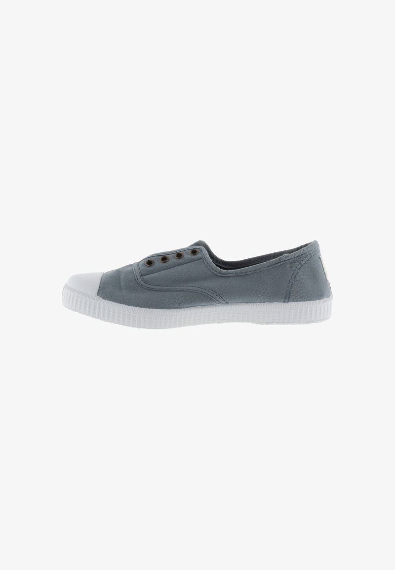 Zapatilla de lona gris sin cordones con una puntera de goma blanca, ojales para ventilación y una suela blanca texturizada.