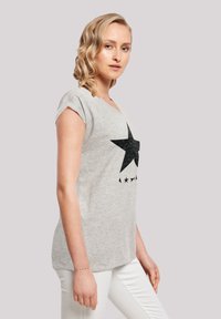 Gray cotton t-shirt with a black star graphic and five small stars below. Features short rolled sleeves and a relaxed fit.