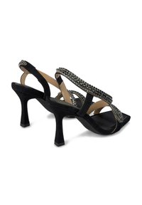 Zwarte suède hoge hak sandalen met kruislings straps, versierd met kleine metalen studs en een vierkante teen. Getextureerde zool.