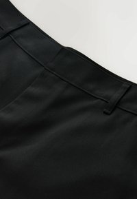 Pantalones negros con cintura plana, textura suave y detalles sutiles en las costuras. La tela parece durable con un acabado mate.
