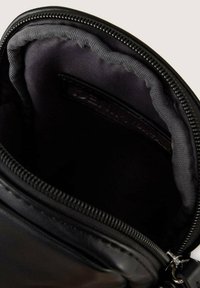 Borsetta in pelle nera con un esterno liscio e un interno in tessuto grigio. Presenta una chiusura a zip e un'etichetta del marchio discreta all'interno.