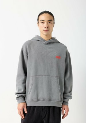 Felpa con cappuccio in cotone grigia con tasca frontale e cappuccio con coulisse. Presenta una piccola grafica rossa sul petto e polsini a coste.