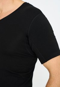 Zwarte T-shirt met korte mouwen van katoen, met een V-hals, zichtbare stiksels en een zachte textuur.