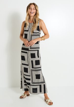 Robe maxi sans manches en noir et crème avec des motifs géométriques carrés. Tissu doux, coupe décontractée, fentes latérales et encolure arrondie.