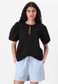 Black textured top with puffed sleeves and a keyhole neckline, paired with light blue striped drawstring shorts.