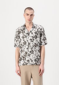 Majica s kratkimi rokavi v črno-beli abstraktni vzorec, zip design, izdelana iz lahkotnega materiala z sproščenim prileganjem.