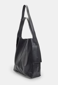 Borsa tote nera in pelle con design morbido, manici lunghi e piatti, e una tasca laterale strutturata. Tessuto liscio con accessori hardware minimi.
