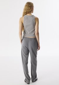 Top a maniche corte grigio attillato e pantaloni grigi larghi, con una texture morbida, vita elastica e un design minimalista senza motivi.
