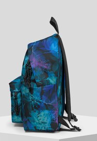Plecak w kwiatowy wzór w odcieniach niebieskiego i fioletowego na czarnym tle, z wyściełanym tyłem i regulowanymi paskami oraz bocznymi kieszeniami.