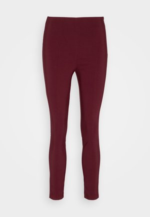 Leggings bordô feitos de tecido elástico, com uma textura suave, corte justo e sem hardware ou padrões visíveis.