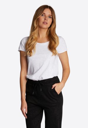 White short-sleeve t-shirt with a rounded neckline, paired with black pants featuring an elastic waistband and pockets. Simple design and fit.