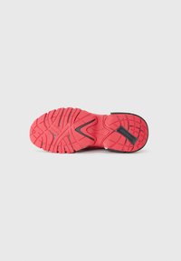 Red athletic shoe outsole featuring a textured rubber surface with a wavy pattern and black accent details near the heel.