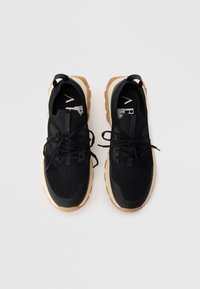 Scarpe sportive nere con tomaia in rete, chiusura con lacci e suola in gomma. Presentano un design testurizzato e una suola dai toni neutri.