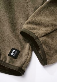 Olive green fleece fabric with a soft texture, featuring dark green accents and a black logo patch on the lower seam.