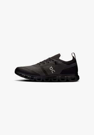 Scarpa da corsa atletica nera con tomaia in mesh, suola segmentata imbottita, chiusura con lacci e piccolo logo bianco sul lato.