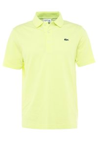 Ponožková košile Lacoste ve světlé žluté barvě, krátké rukávy, dvouknoflíková léga, s zeleným logem krokodýla na levé části hrudníku.