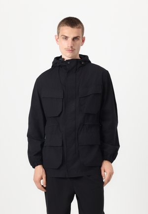 Black hooded jacket with two chest and two side pockets, elastic cuffs, front zipper closure, made of lightweight fabric.