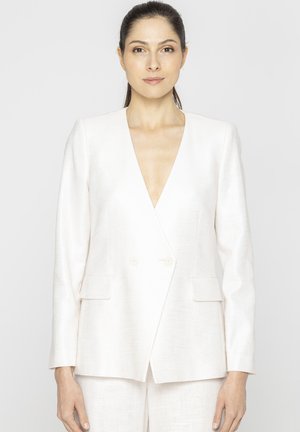 Biały lniany żakiet z głębokim dekoltem w serek, podwójnymi guzikami i dwoma kieszeniami z przodu; gładka tekstura i minimalistyczny design.