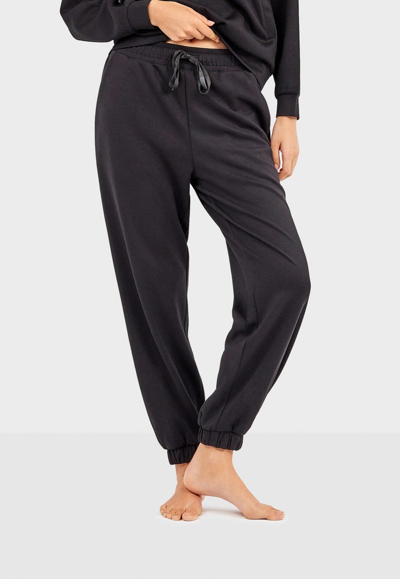 Sorte sweatpants lavet af blødt stof, med elastisk talje og snor samt afsluttede ankler for en afslappet pasform.