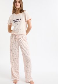 Jasnoróżowy zestaw piżamowy składający się z krótkiego rękawa koszulki z nadrukiem oraz luźnych, wzorzystych spodni z motywami małych koktajli.