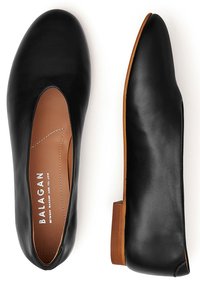 Ballerine in pelle nera con punta tonda, dettagli ritagliati e tacco basso in legno. L'interno presenta una fodera liscia color tan e il marchio.
