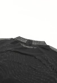 Black mesh garment with a textured surface, featuring a dotted embellishment along the neckline and a keyhole opening at the back.