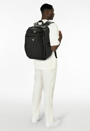 Zwarte gewatteerde rugzak van gestructureerd materiaal, voorzien van een zilveren logo, dubbele rits en verstelbare, gevoerde riemen.