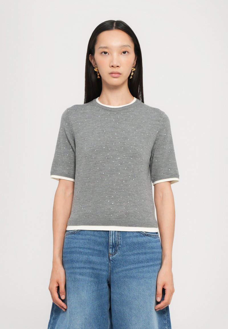 Gray knit short-sleeve top with dotted texture, white collar and hem accents, paired with wide-leg blue denim.