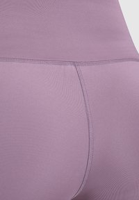 Hoge taille leggings van zacht lavendelkleurig materiaal, met een gladde textuur en versterkte stiksels langs de naden voor duurzaamheid.