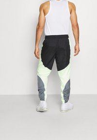 Farbblockierte Jogginghosen in Schwarz, Hellgrün und Grau. Elastischer Bund mit Kordelzug, zulaufende Bündchen und atmungsaktives Material.